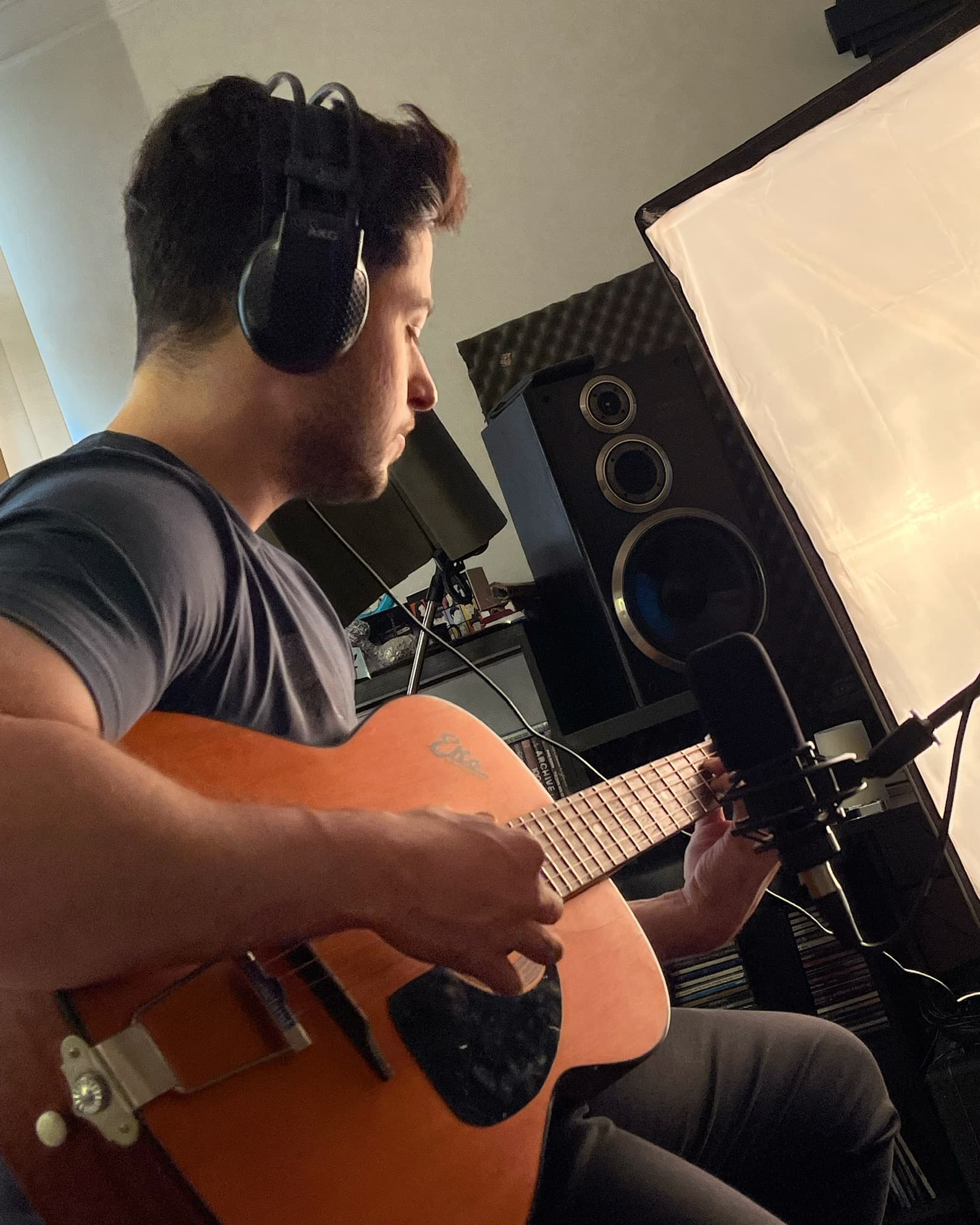 Ali Diaan in a home studio, playing an acoustic guitar.
