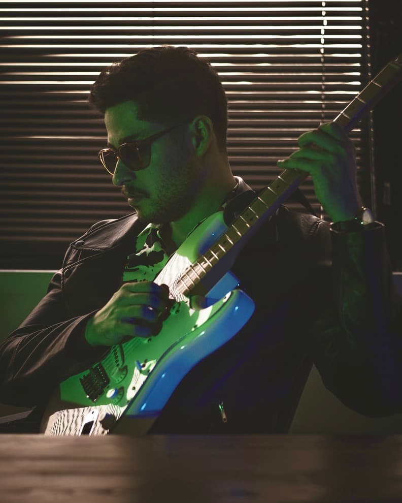 A stylized photo of Ali Diaan playing an electric guitar.
